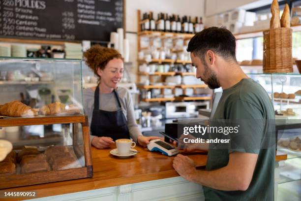 man making a mobile payment at a cafe - tikken en betalen stockfoto's en -beelden
