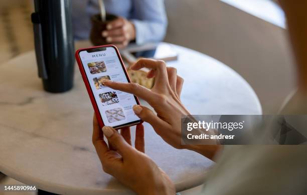 donna ad un caffè che guarda un menu digitale - ordine foto e immagini stock