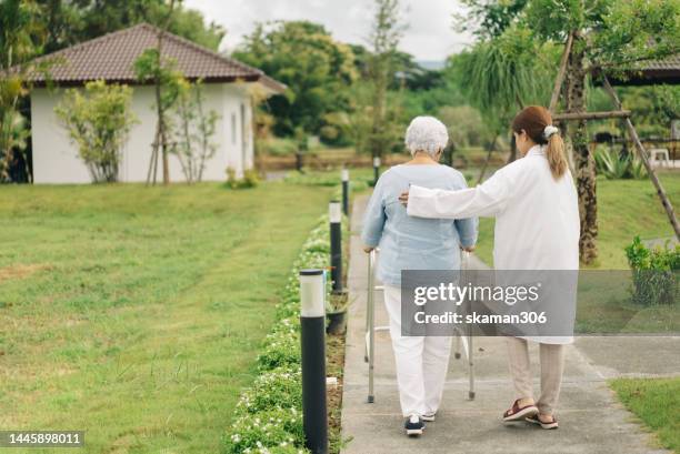 positive emotion asian physical therapist support asian seniors practice walking with mobility walkers at health care center - invecchiamento della popolazione foto e immagini stock