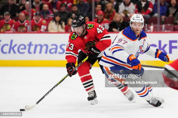 Colin Blackwell of the Chicago Blackhawks skates with the puck against Connor McDavid of the Edmonton Oilers during the second period at United...