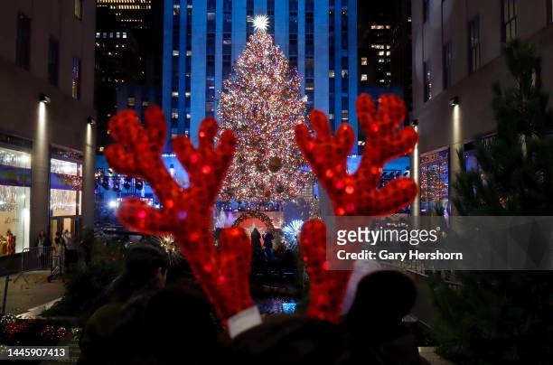 Person wearing a pair of antlers stands in front of the Rockefeller Center Christmas tree after it was lit on November 30 in New York City.
