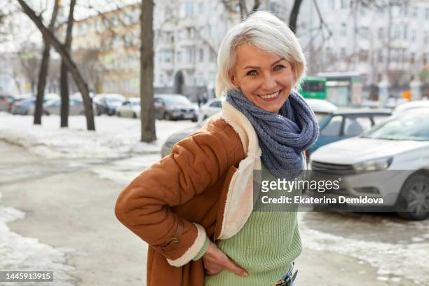 happy senior woman happy on winter street - blue coat stock-fotos und bilder