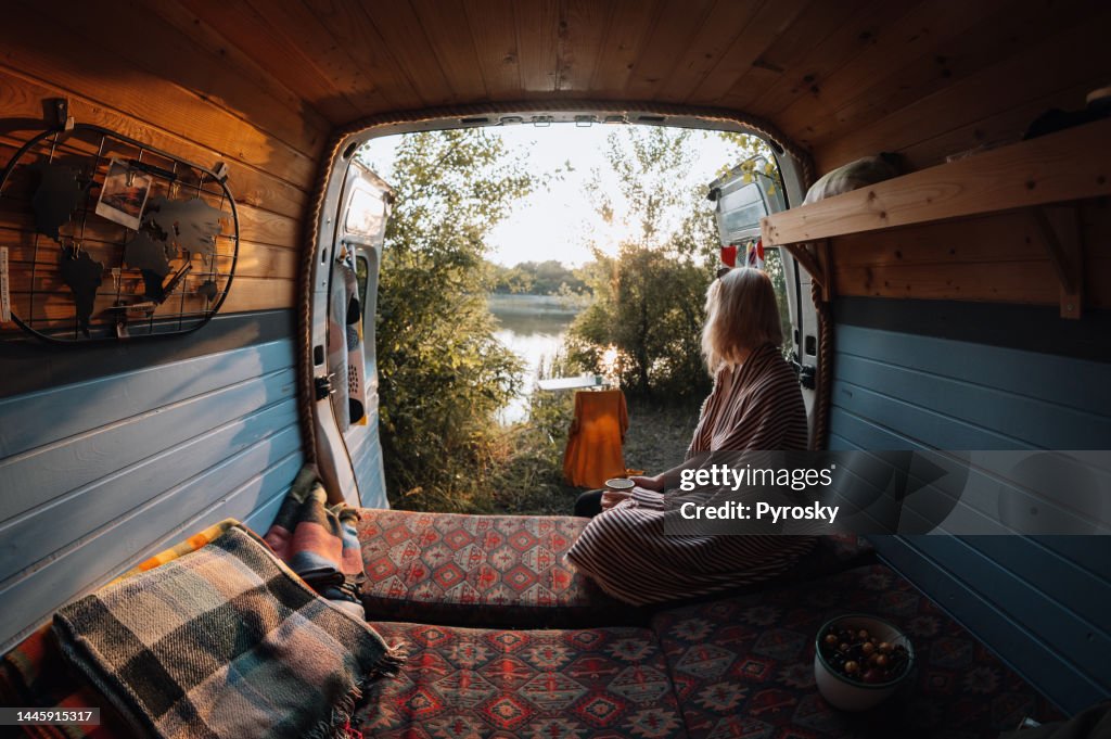 Woman enjoys coffee from her van