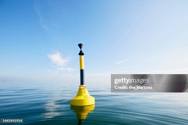 black yellow striped buoy in smooth sea against blue sky - ブイ ストックフォトと画像