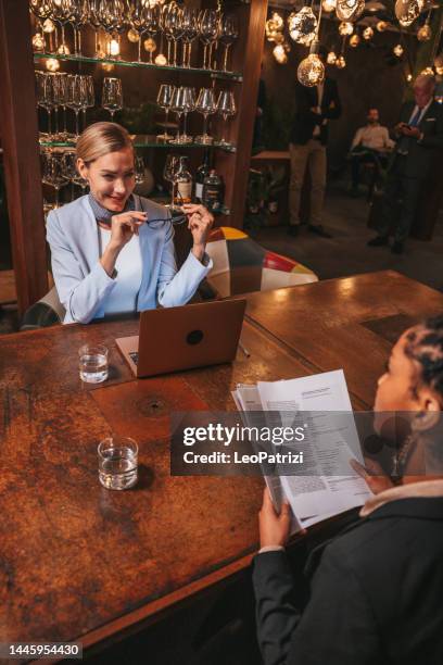 two women signing an agreement after a business job interview in a luxury restaurant - hotel confirmation stock pictures, royalty-free photos & images