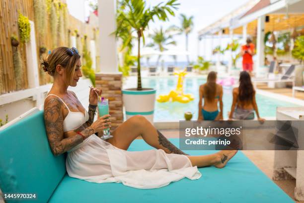 caucasian woman lying on the pool bed, and drinking cocktails - poolside stock pictures, royalty-free photos & images