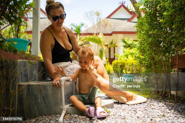 petit garçon jouant avec un robinet à la station touristique avec sa mère - province de surat thani photos et images de collection