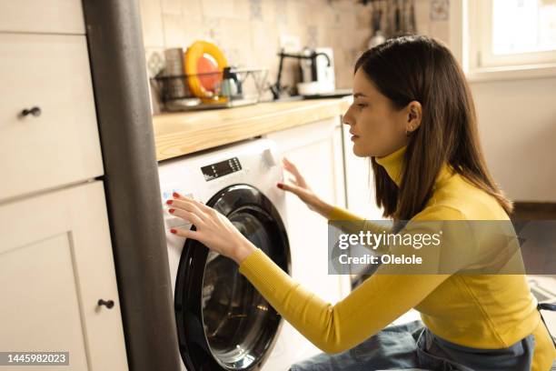 happy young woman adjusting a washing machine at her house - switching off machine stock pictures, royalty-free photos & images