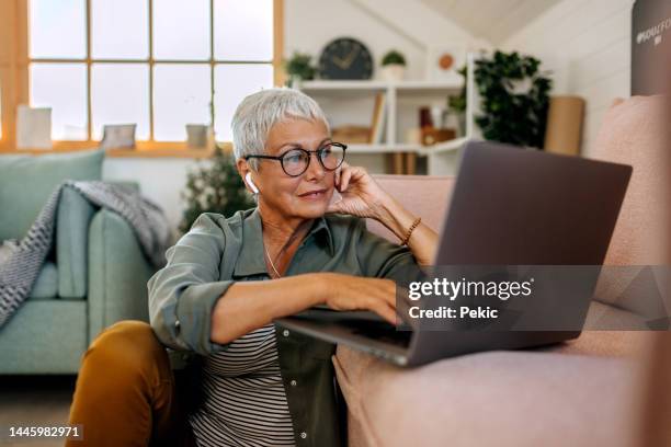 seniorin mit laptop auf wohnzimmerboden - middle aged woman at home stock-fotos und bilder