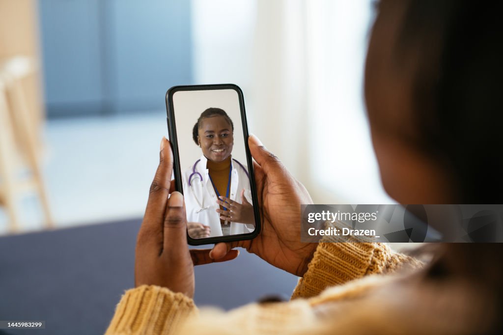 Unrecognisable African woman using digital device during illness, talking to doctor on video call