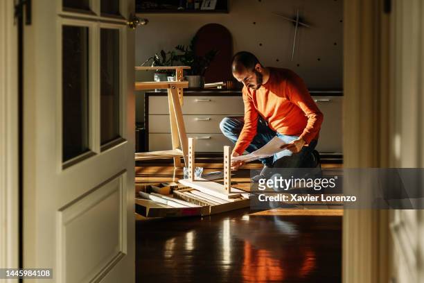 young adult man assembling new trestle furniture in the morning at home - making stock-fotos und bilder