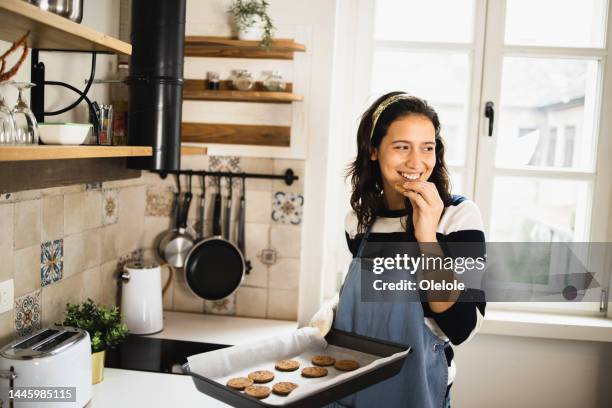 portrait of a beautiful girl tasting hot cookies - baking stock pictures, royalty-free photos & images
