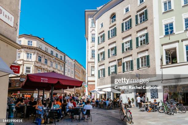 people sitting at cafeteria terraces on the streets of the historic center of salzburg (altstadt). - salzburgo stock-fotos und bilder