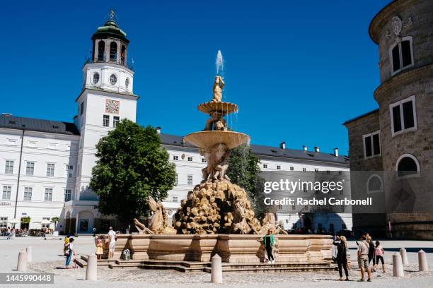 people taking photos in residence square (residenzplatz) with neue residenz (right), the beautiful residence fountain (residenz fountain) (center)and salzburg cathedral (right). - salzburgo stock-fotos und bilder