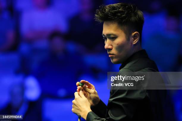 Cao Yupeng of China chalks the cue during the first round match against John Higgins of Scotland on day three of the 2022 BetVictor Scottish Open at...