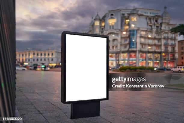 blank city format (lightposter, citylight) banner on the sidewalk in the night city street mockup.  pylon, a free-standing light box ready for your content - digital display ad stock pictures, royalty-free photos & images