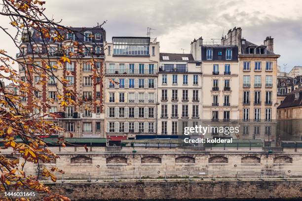 old row houses exteriors on embankment of seine in paris in autumn - boulevard stock pictures, royalty-free photos & images