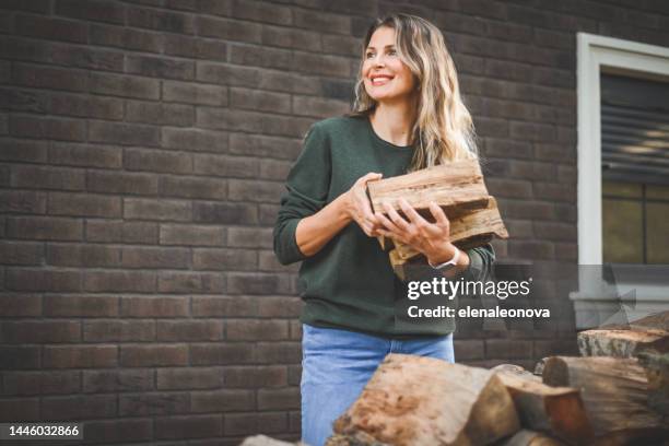femme adulte mûre portant du bois de chauffage - bois de chauffage photos et images de collection