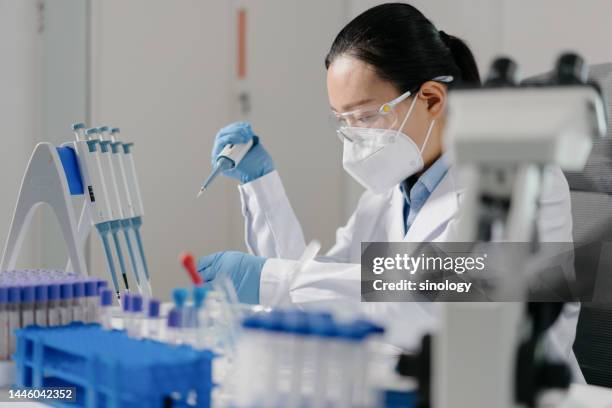 scientist adding reagents to centrifuge tubes in laboratory - blood group stock-fotos und bilder