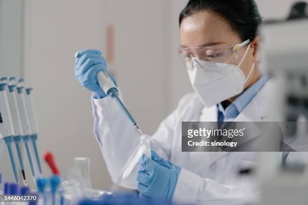 scientist adding reagents to centrifuge tubes in laboratory - inmunologia fotografías e imágenes de stock