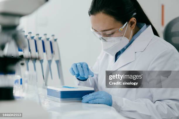 scientist loading centrifuge tubes in laboratory - tubo equipamento de laboratório - fotografias e filmes do acervo
