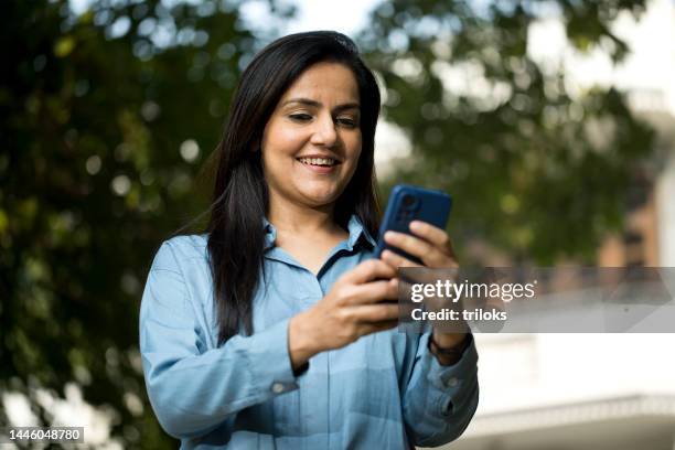 smiling woman texting over mobile phone - south asia stock pictures, royalty-free photos & images
