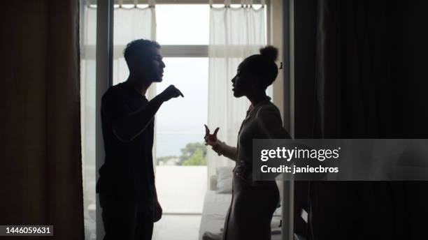 unhappy african ethnicity couple fighting and gesturing in the living room. relationship crisis - menselijke relaties stockfoto's en -beelden