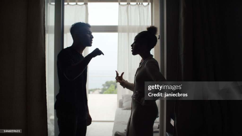 Unhappy african ethnicity couple fighting and gesturing in the living room. Relationship crisis