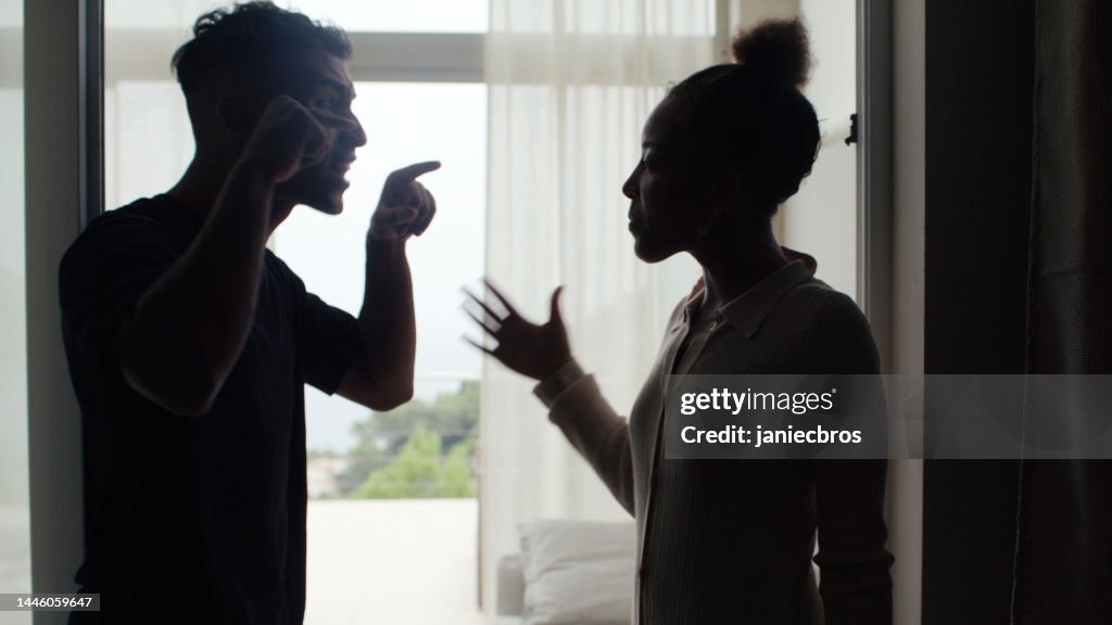 Unhappy african ethnicity couple fighting and gesturing in the living room. Marriage breakup