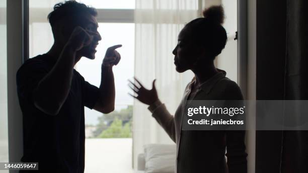 unhappy african ethnicity couple fighting and gesturing in the living room. marriage breakup - gevecht stockfoto's en -beelden