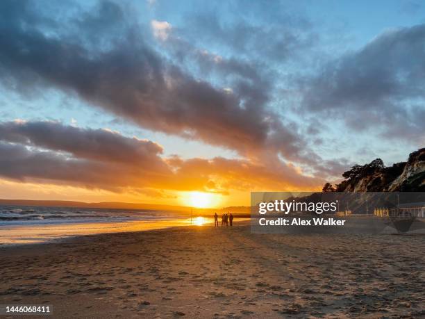 dramatic sunset on large beach with distant figures, bournemouth, uk - dorset uk - fotografias e filmes do acervo