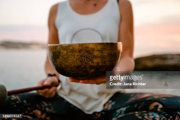 slim woman holds singing bowl in her hands - closeup - guru imagens e fotografias de stock