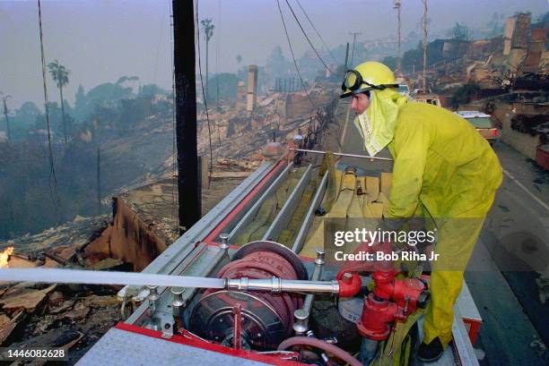 Chimneys and smoldering homes are all that remain the morning after a wildland fire fed by heavy-winds damaged many hillside homes in the beach...