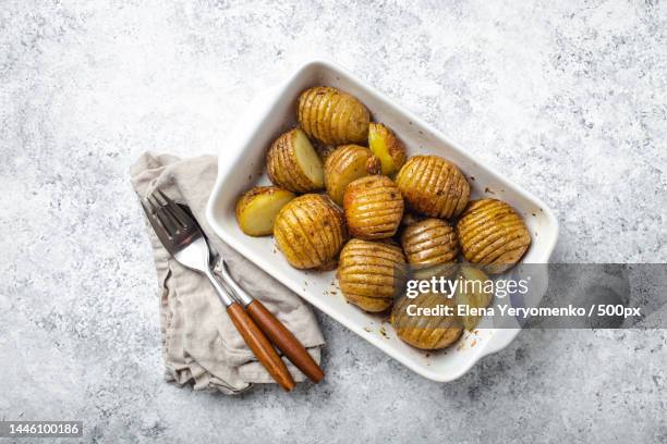 hasselback baked potatoes in white ceramic casserole dish on white - keyboard white stockfoto's en -beelden