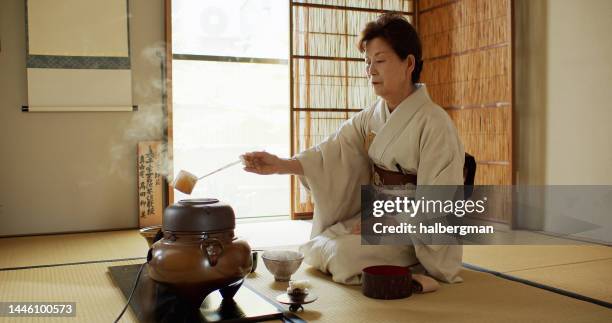 elderly tea ceremony host measuring out hot water - traditional ceremony stock pictures, royalty-free photos & images