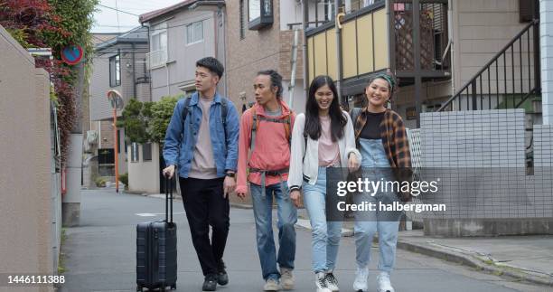 fun asian travelers walking down tokyo street together - sabbatical stockfoto's en -beelden