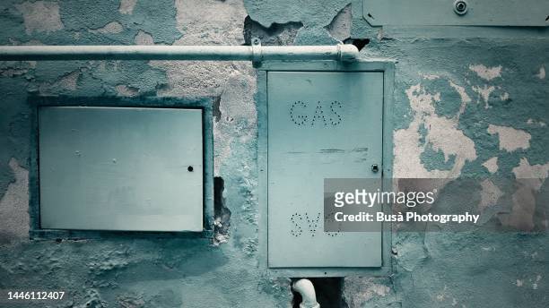 gas box with pipes on dilpidated wall with peeling colored paint - meter foto e immagini stock