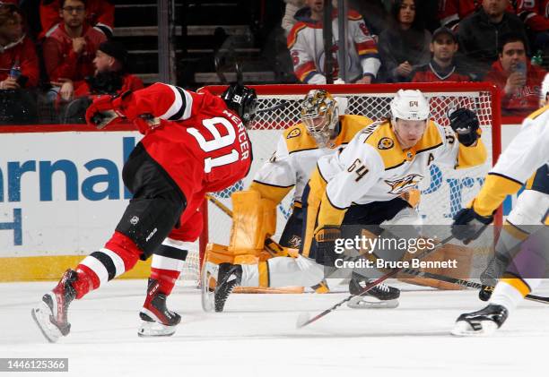 Juuse Saros and Mikael Granlund of the Nashville Predators defend against Dawson Mercer of the New Jersey Devils during the first period at the...