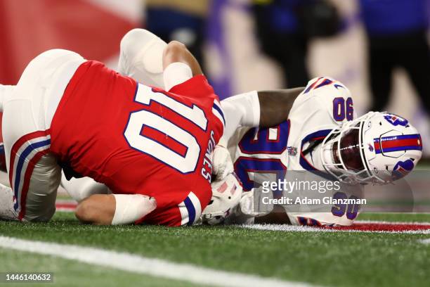 Defensive end Shaq Lawson of the Buffalo Bills hits quarterback Mac Jones of the New England Patriots after throwing a second quarter pass at...
