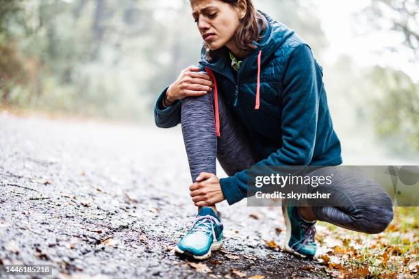 athletic woman injured her leg at the park. - injured leg stock pictures, royalty-free photos & images