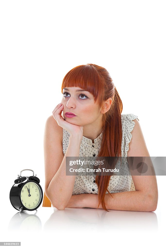 Young woman sitting with alarm clock