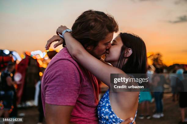 pareja joven besándose en un parque de diversiones - beso en la boca fotografías e imágenes de stock