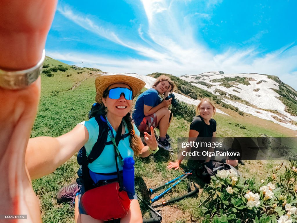 Female friends hikers relax during a hike in the mountains and take selfie.