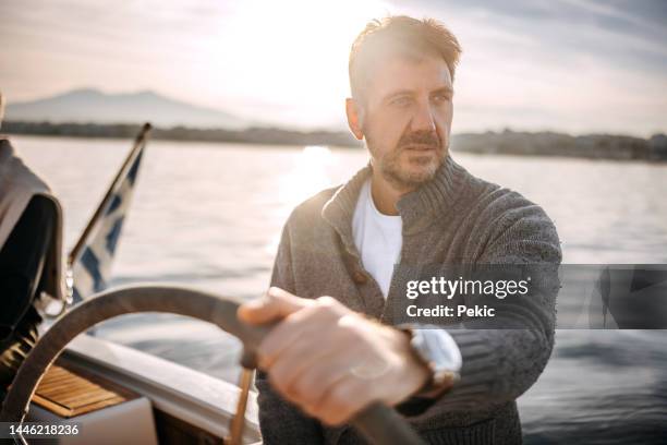 handsome mature man sailing his yacht on vacation - cardigan sweater stock pictures, royalty-free photos & images