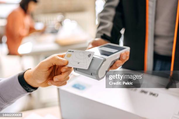 nahaufnahme der hand eines mannes, der die lieferung mit kreditkarte in einem büro bezahlt, scannen auf einem kartenautomaten - poes stock-fotos und bilder