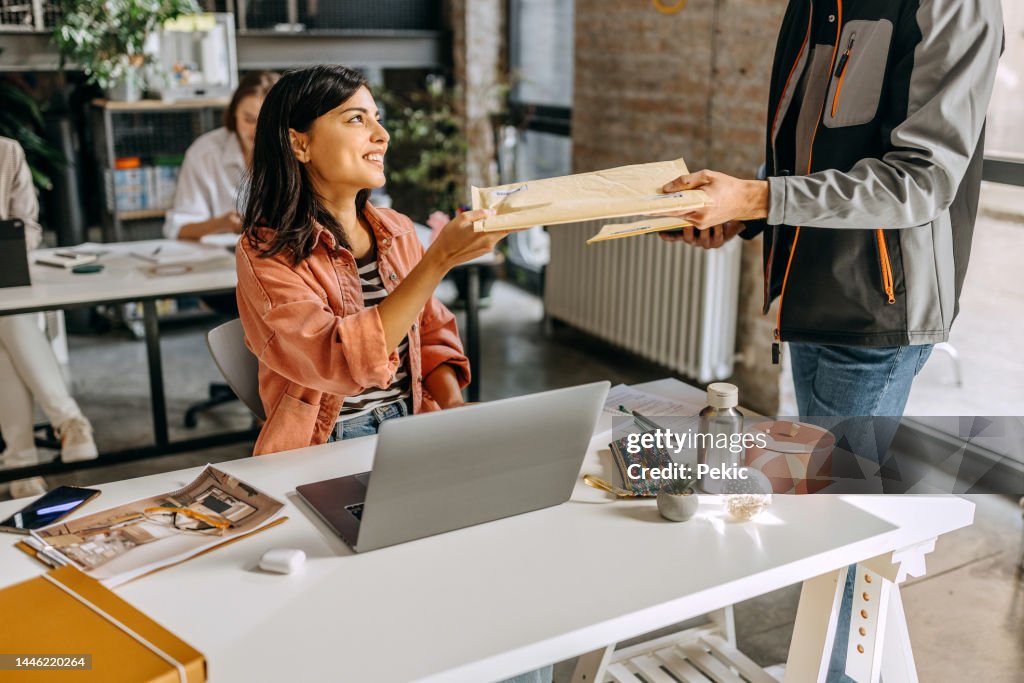 Delivery guy delivering mail to woman in the office