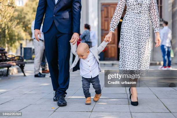 madre y padre con su bebé saliendo de la iglesia - iglesia fotografías e imágenes de stock