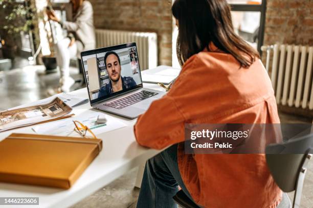 young casually clothed woman on a video call in the office - employee engagement remote stock pictures, royalty-free photos & images