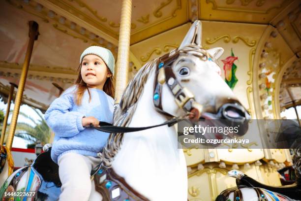 hübsches kind auf karussellpferd. süßes mädchen ist reitattraktion. lustige feier - zirkus kinder stock-fotos und bilder