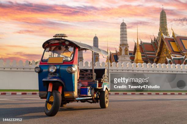 traditional thai taxi or tuk tuk with wat phra kaeo and grand palace in the background - jinrikisha stock pictures, royalty-free photos & images